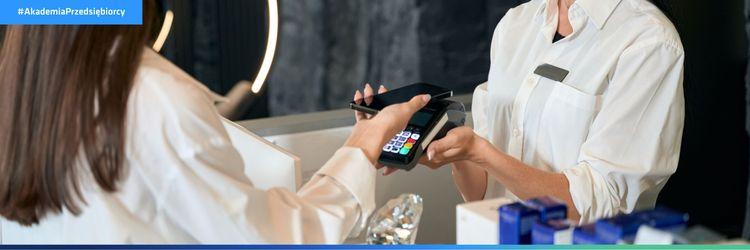 Kobieta płaci telefonem za usługę – sposób na niższe koszty prowadzenia salonu