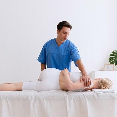 Fizjoterapeuta wykonujący zabieg pacjentce leżącej na stole do masażu